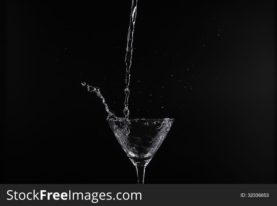 Pouring water into glass with black background. Pouring water into glass with black background