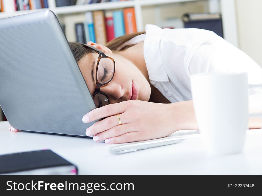 Woman sleeping on her laptop in the workplace