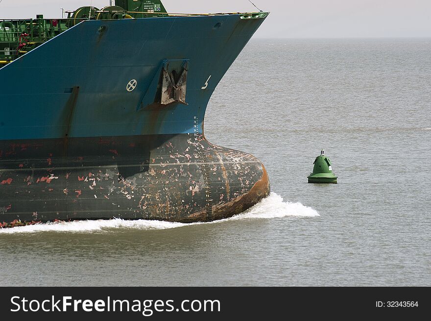 Bulbous bow of unladen cargo vessel under way with green navigation buoy. Bulbous bow of unladen cargo vessel under way with green navigation buoy.