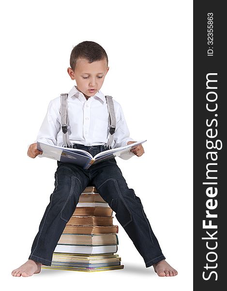 Boy sitting on a pile of books and reading