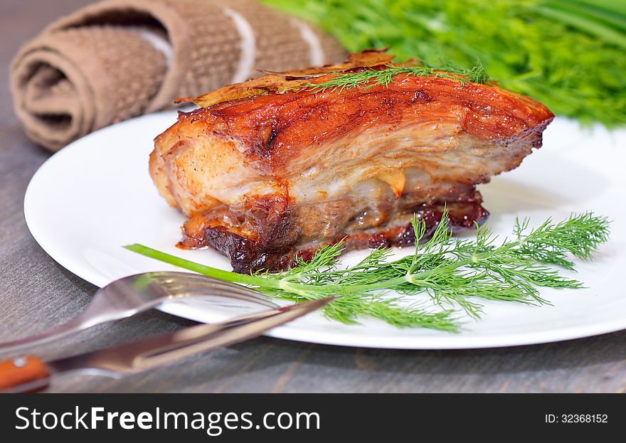 Dish with baked bacon decorated with greenery of sveniny. Dish with baked bacon decorated with greenery of sveniny