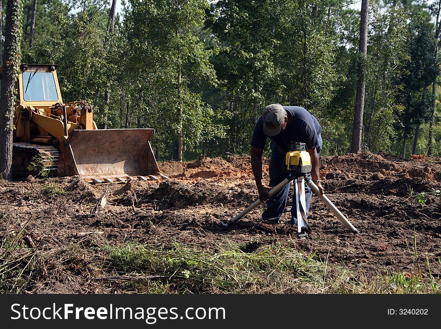 Construction worker setting transit level on home construction site. Construction worker setting transit level on home construction site