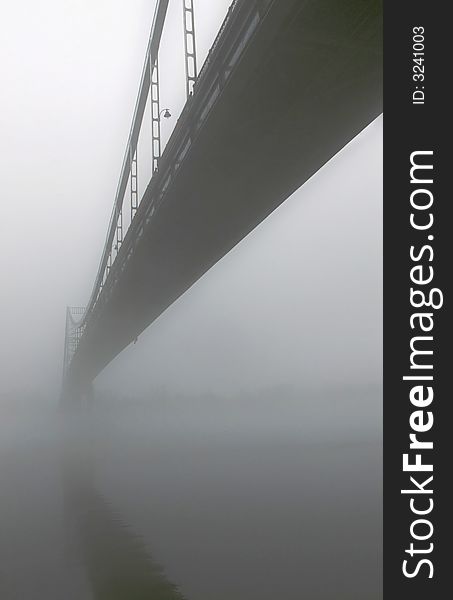 View of entire length of bridge with fog obscuring top of bridge.