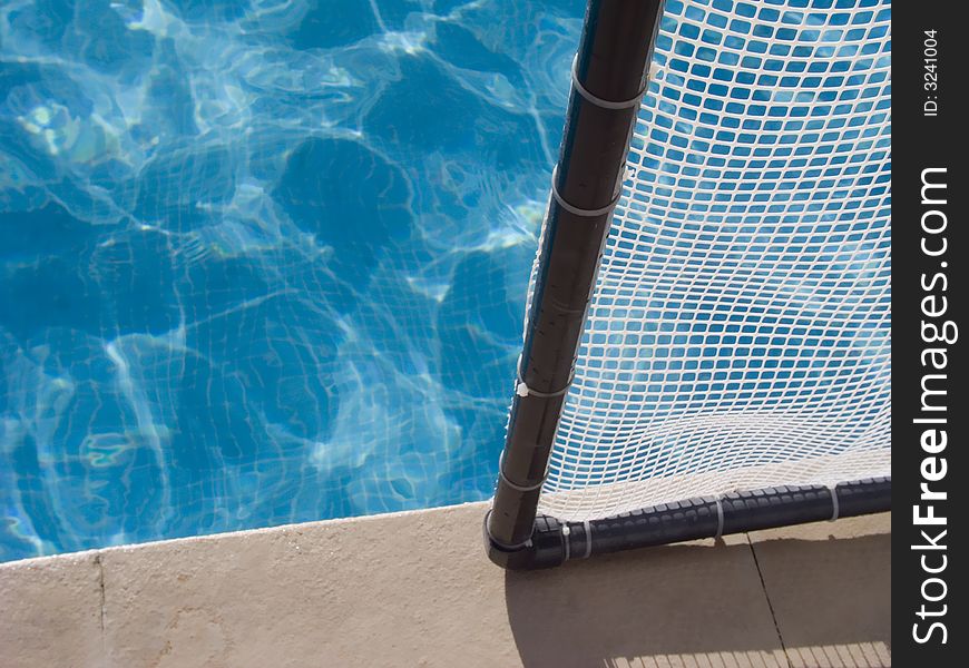 Detail of a render of football, in the border of the pool, with blue water as a background. Detail of a render of football, in the border of the pool, with blue water as a background