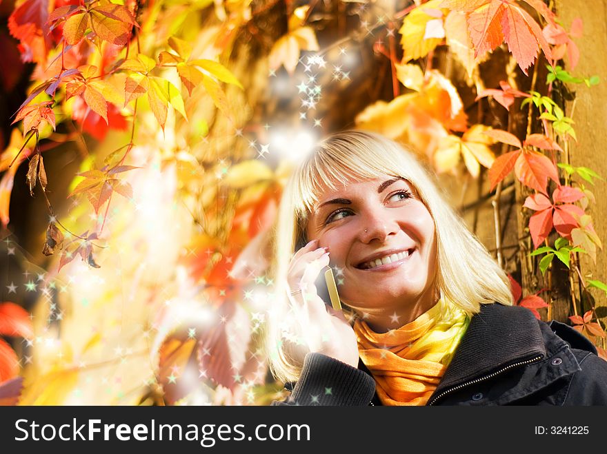 Happy girl talks on the phone, abstract autumn background behind her