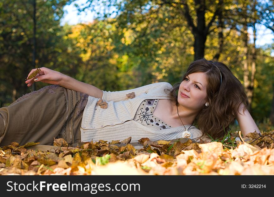 Girl lying on autumn leaves in park. Girl lying on autumn leaves in park