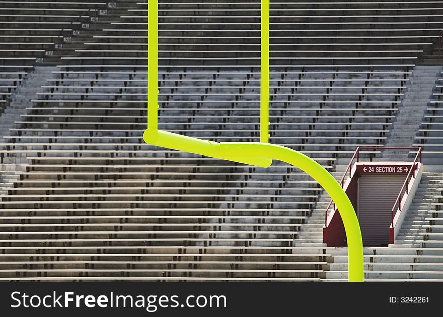 Green goal posts in front of deserted stadium seats. Green goal posts in front of deserted stadium seats.
