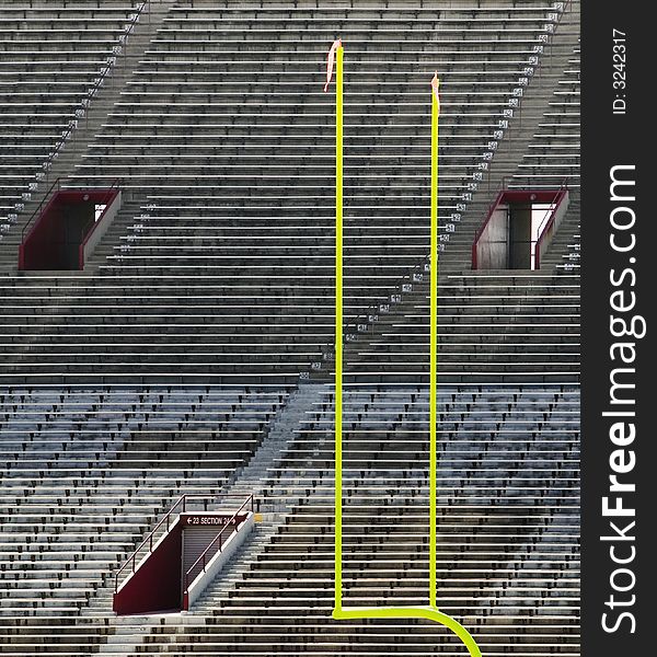 Green goal posts in front of deserted stadium seats. Green goal posts in front of deserted stadium seats.