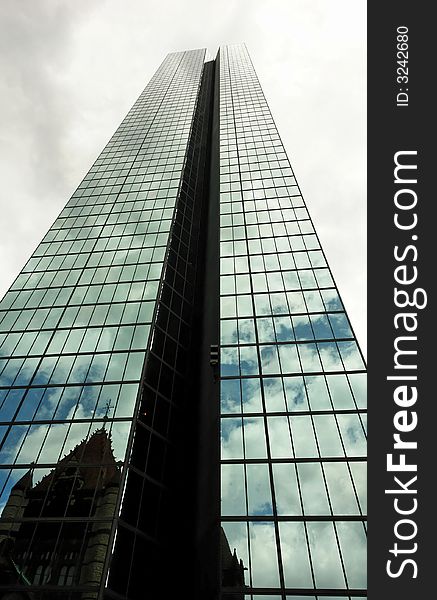 Office skyscraper reaches high into the sky towering over church reflected in the mirrored panels of glass. Office skyscraper reaches high into the sky towering over church reflected in the mirrored panels of glass