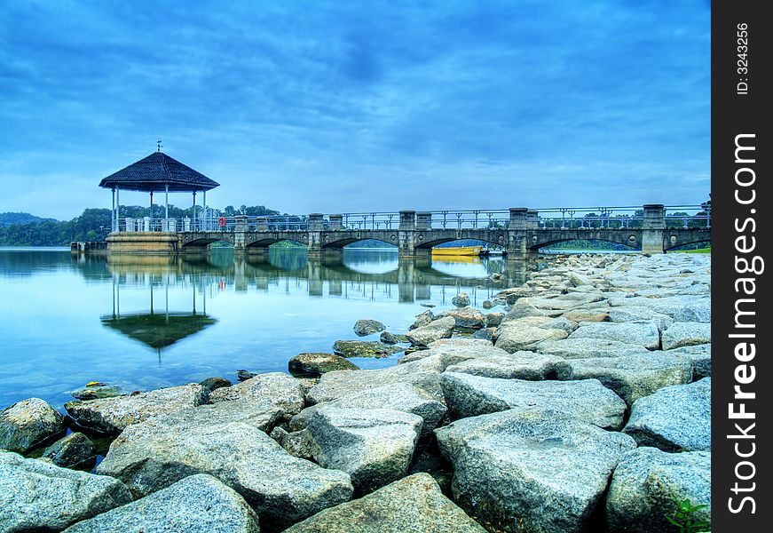 A pavilion projecting into the clam surface of a reservoir on an overcast day