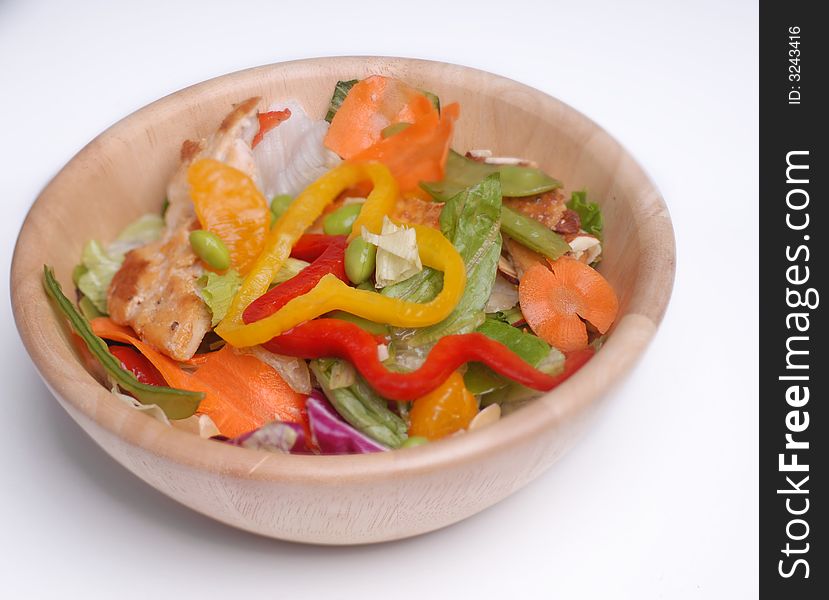 Delicious healthy salad with chicken as a protein in a wooden bowl.