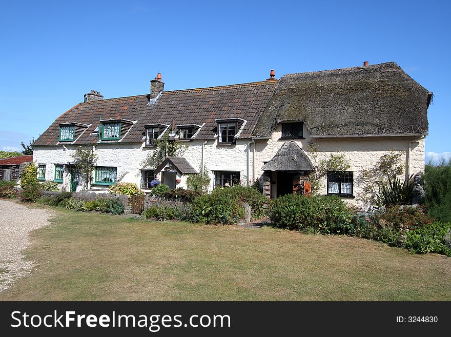 A Row of Whitewashed English Rural Cottages and gardens againt a clear blue sky. A Row of Whitewashed English Rural Cottages and gardens againt a clear blue sky