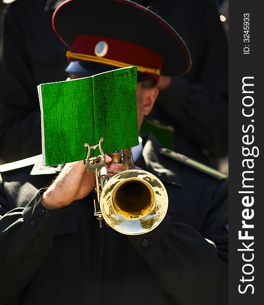 The man in uniform plays on a trumpet. The man in uniform plays on a trumpet