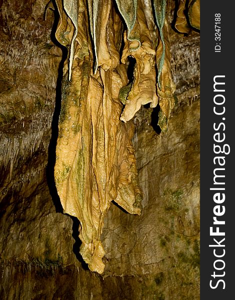 Large sandstone stalactites hang from the ceiling in Smoke Hole Caverns, WV. The green shading is cave moss or algae.