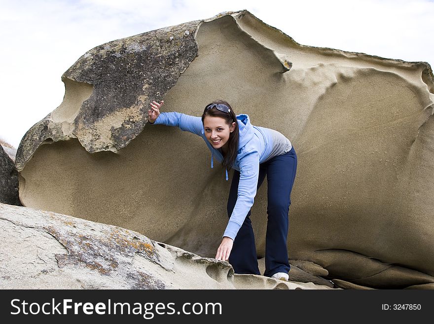 A pretty young woman climbs over sandstone rock. A pretty young woman climbs over sandstone rock.