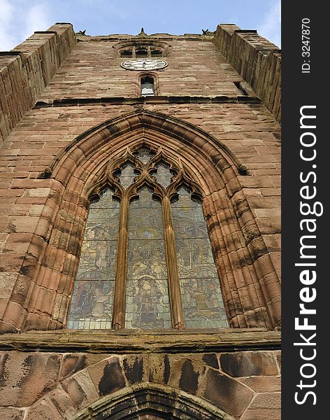 Medieval village church made from sandstone with stained glass windows and a clockface.