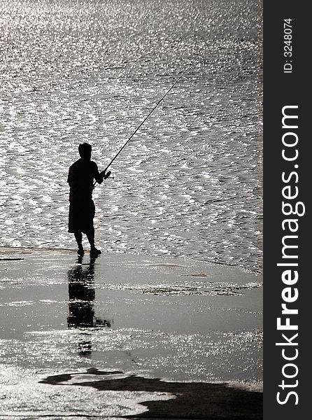 Man fishing at the beach in a sunny day. Man fishing at the beach in a sunny day.
