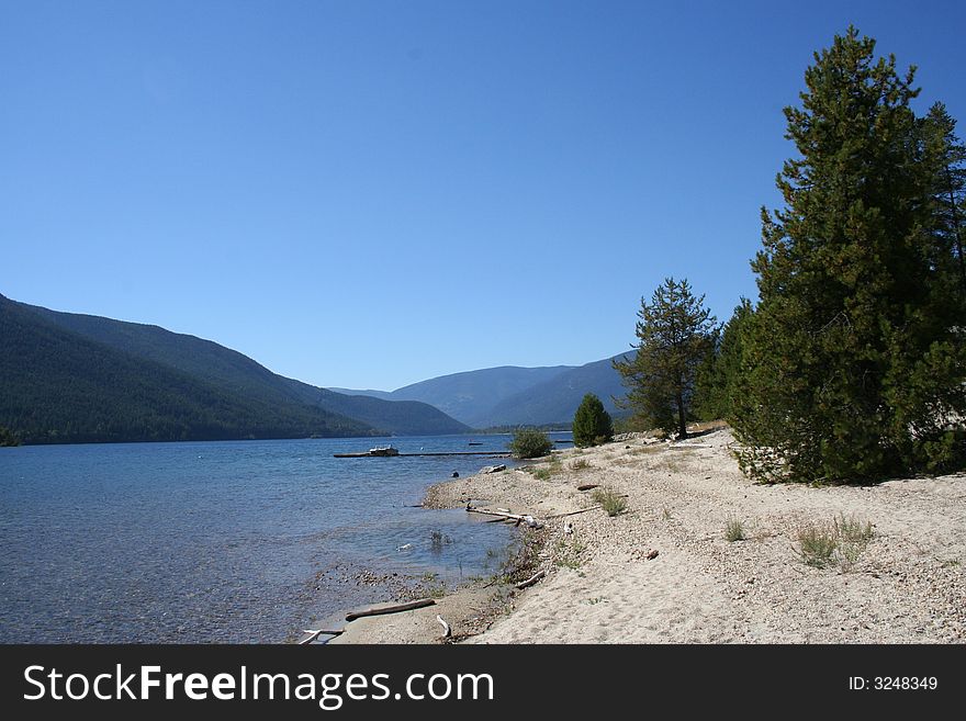 Blue water, sand, trees and mountains lanes in the back. Blue water, sand, trees and mountains lanes in the back