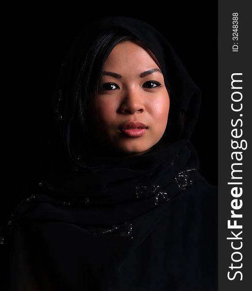 A Beautiful Asian shy looking girl over black with a balck scarf over her head. A Beautiful Asian shy looking girl over black with a balck scarf over her head