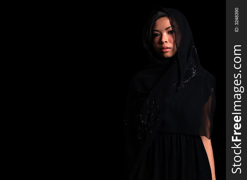 A Beautiful Asian shy looking girl over black with a black scarf over her head (lot's of copy space). A Beautiful Asian shy looking girl over black with a black scarf over her head (lot's of copy space)