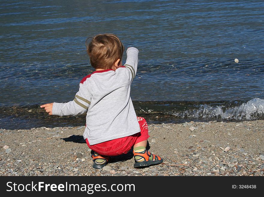 Small boy throwing stones in the water. Small boy throwing stones in the water