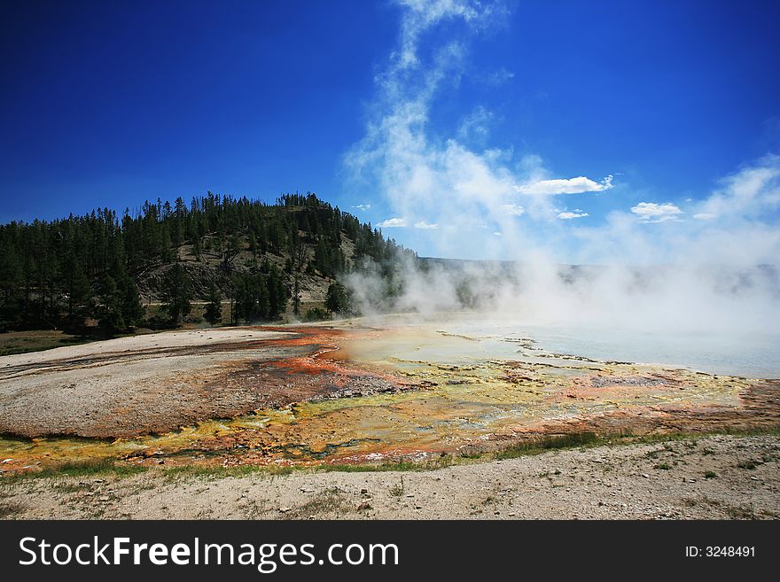Midway geyser in yellowstone. the mist is from a hot spring