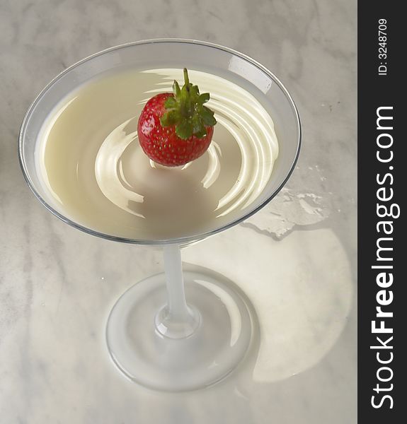 Falling strawberry in a glass with milk