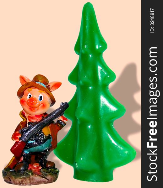 The toy hunter-pig at a fur-tree isolated over pink background