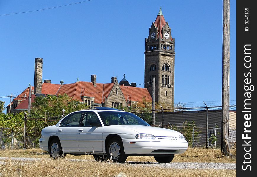 A white Chevrolet Lumina in front of a large brick building with a clock tower. A white Chevrolet Lumina in front of a large brick building with a clock tower.