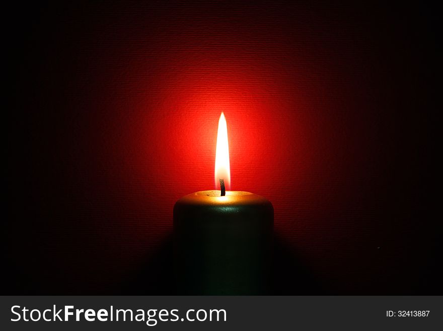 Burning gold candle on the red background. Burning gold candle on the red background