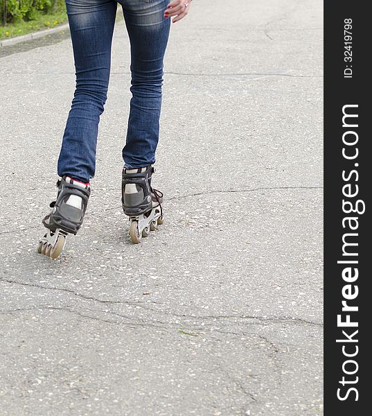 Girl rides on roller skates on asphalt. Legs in rollers