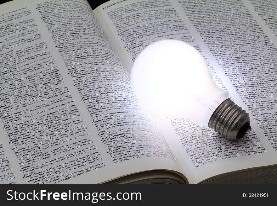 Illuminated light bulb glowing on a book