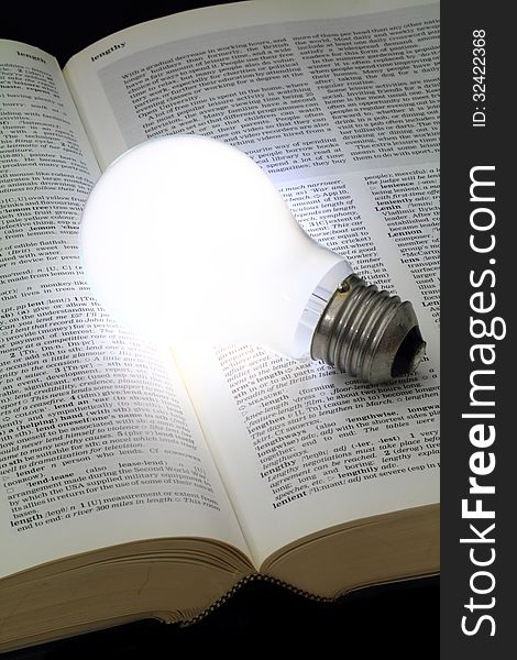 Illuminated light bulb glowing on a book