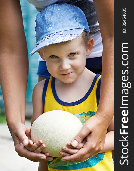 Little boy holding an ostrich egg together his mother. Little boy holding an ostrich egg together his mother