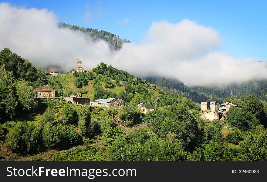 Mountain village with ancient towers in morning fog
