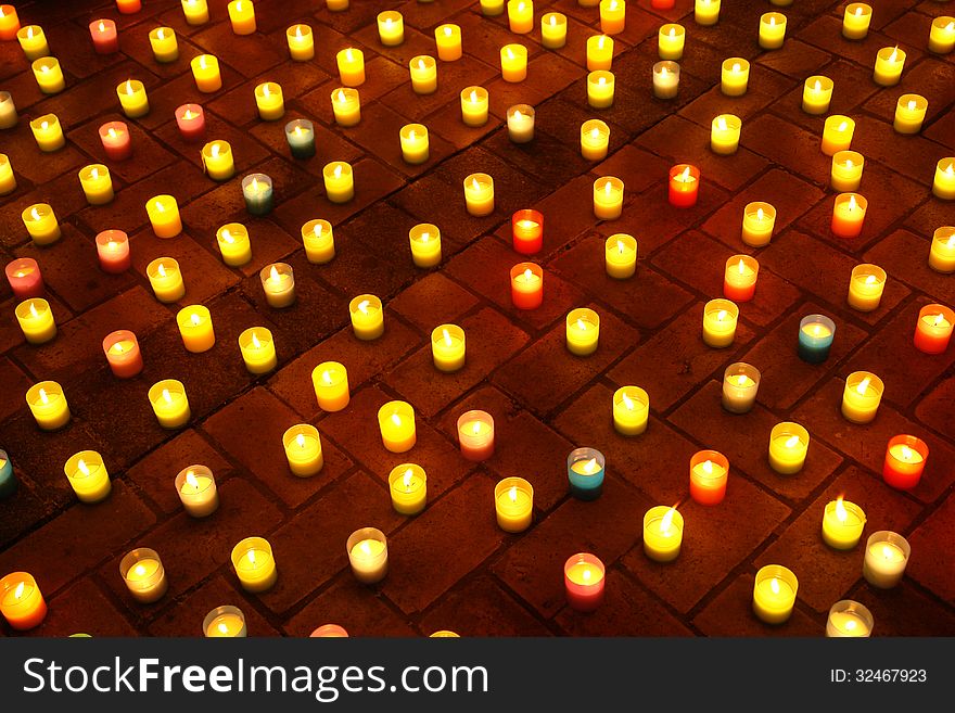 Multicolored lighted candles on the sidewalk at night. Multicolored lighted candles on the sidewalk at night