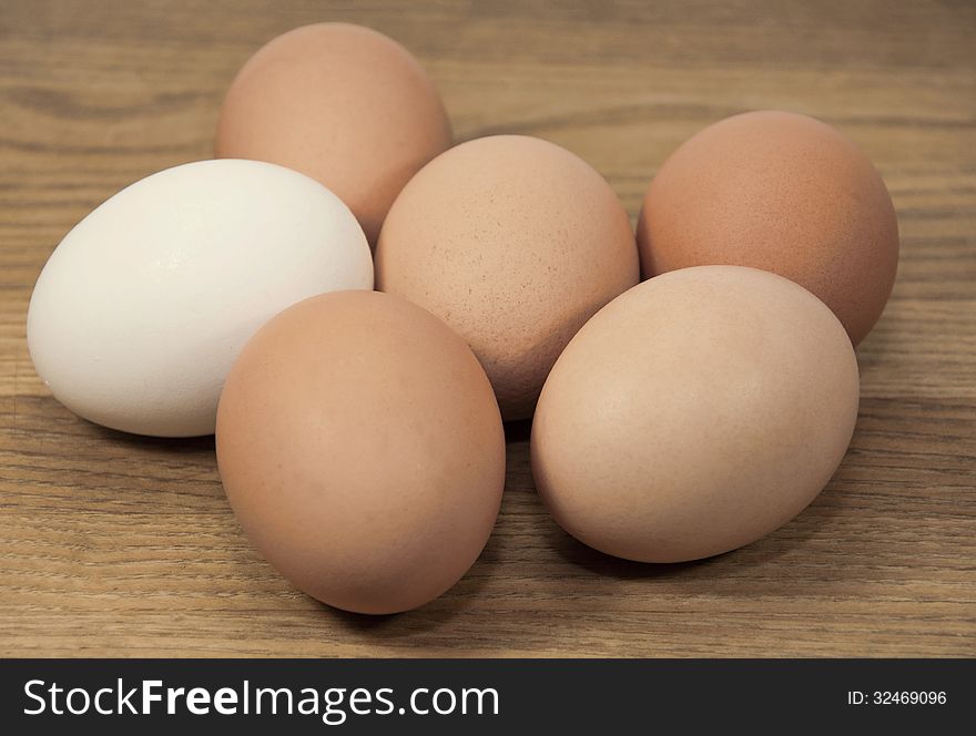 Group of brown and white eggs against a brown wood grained background. Group of brown and white eggs against a brown wood grained background