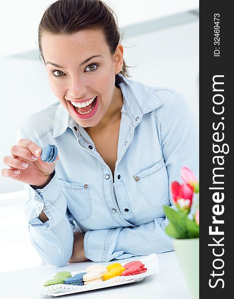 Beautiful woman eating french cookies at home