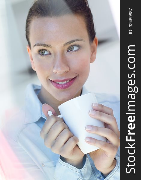 Beautiful young woman having a coffee at the kitchen