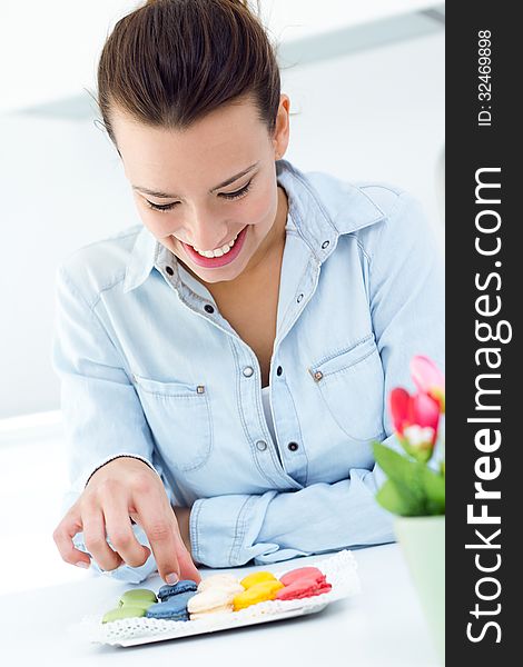 Beautiful woman eating french cookies at home