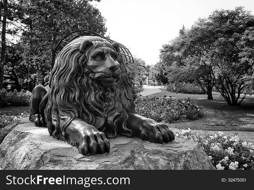 Lion statue guarding the entrance of the rose garden at the Montreal botanical garden in black and white