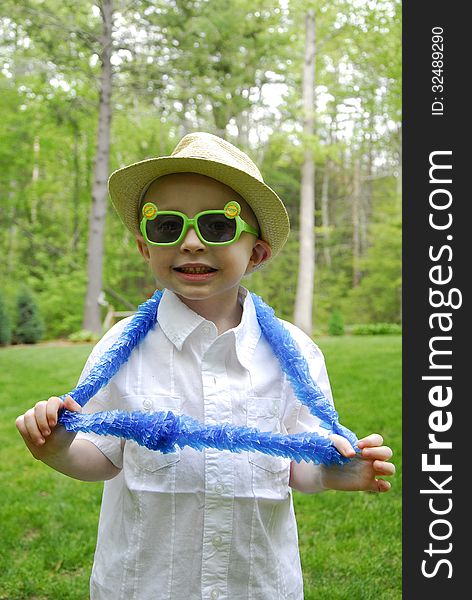 A little boy wears plastic sun glasses and blue hawaian lei. A little boy wears plastic sun glasses and blue hawaian lei