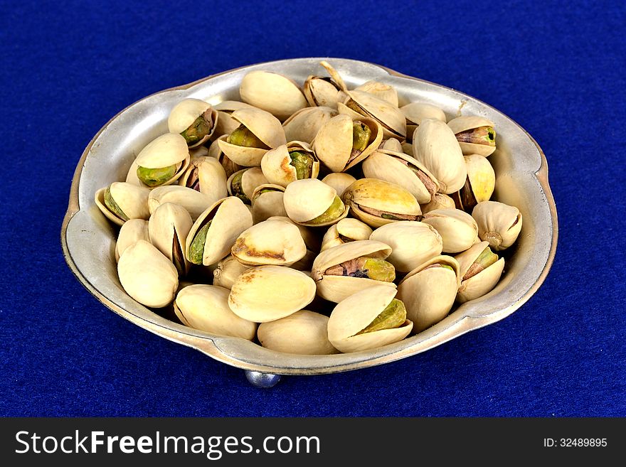 A small metal dish of pistachios in the shell.