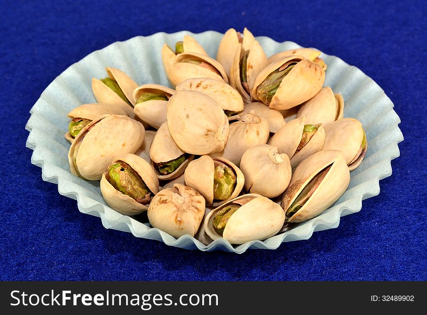 Pistachios in the shell in a blue paper cup.