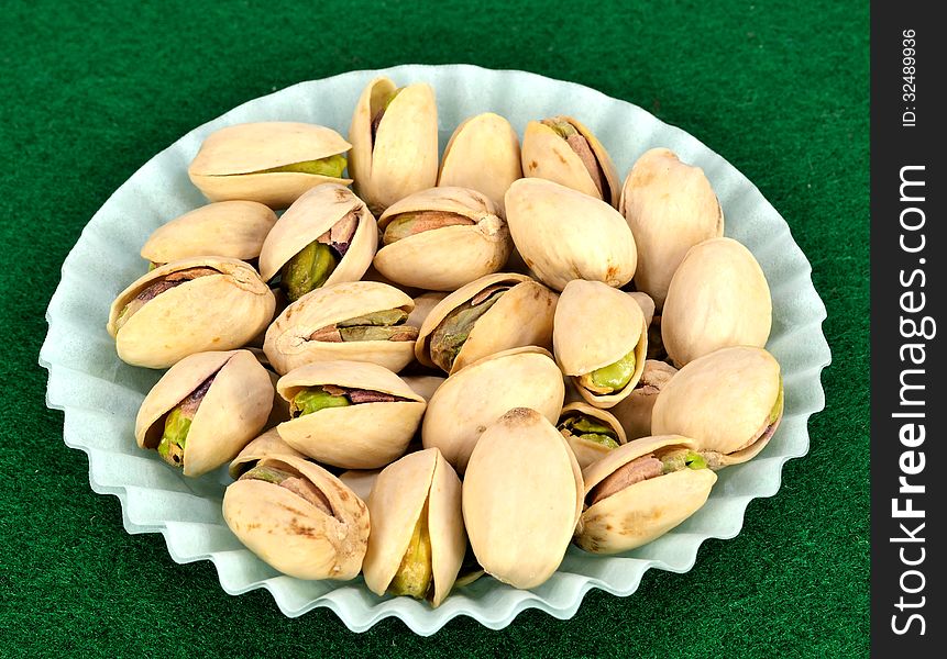 Pistachios in the shell in a blue paper cup.