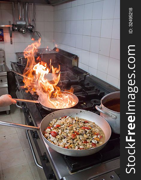 Cooking seafood with tomatoes for pizza in Italian pizzeria and fire view in a pan while frying onion. Cooking seafood with tomatoes for pizza in Italian pizzeria and fire view in a pan while frying onion.