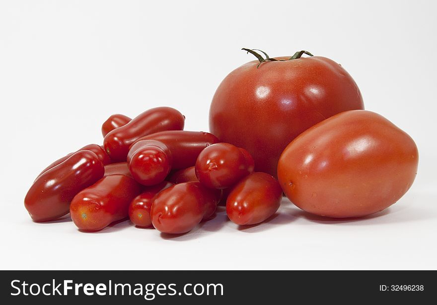 Group of three types and sizes of red tomatoes against a white background. Group of three types and sizes of red tomatoes against a white background