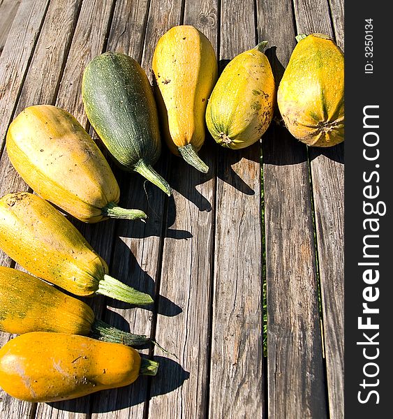 Semicircle from vegetable marrows on a wooden table. Semicircle from vegetable marrows on a wooden table