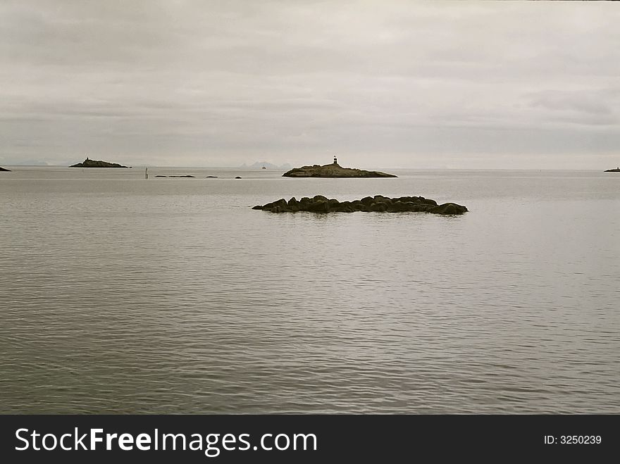 Sea and small islands in Norway. Gray cloudy sky.