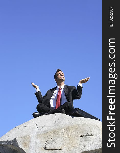 Businessman outdoors on a rock meditating. Businessman outdoors on a rock meditating